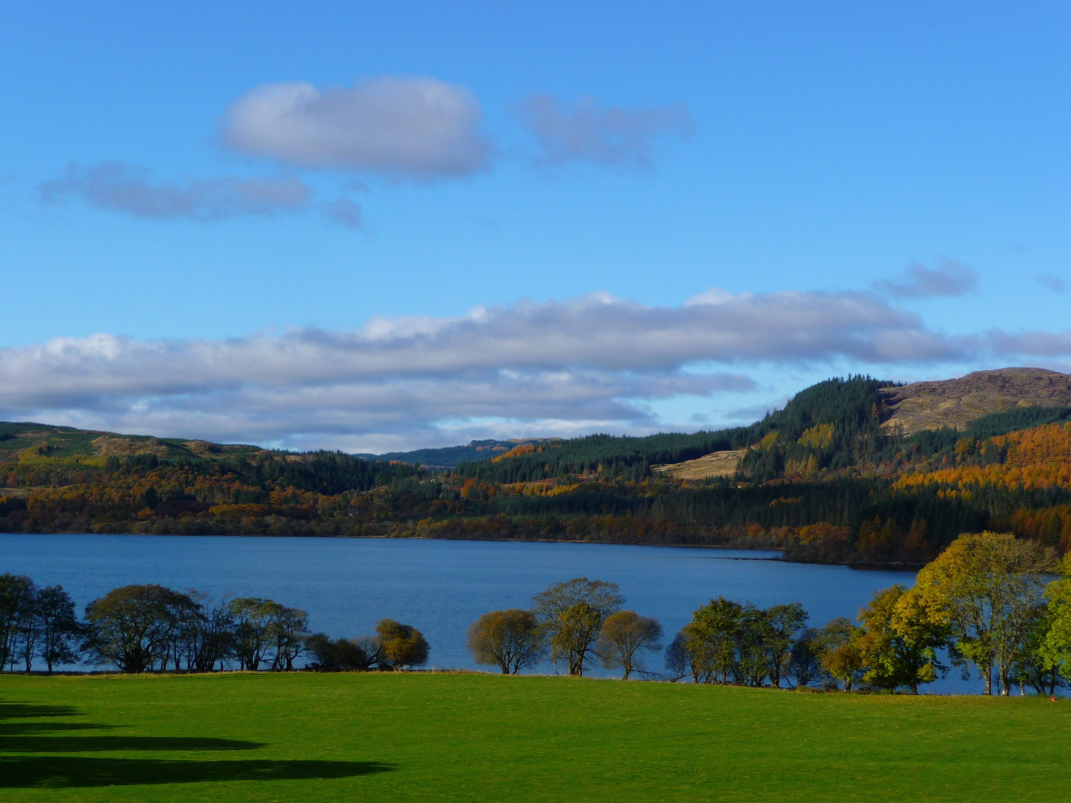 A lake surrounded by hills with trees in autumn colors.