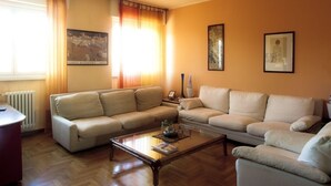 A living room with two beige sofas, a wooden coffee table, and a radiator.