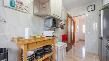 A kitchen with a microwave, toaster, and a wooden shelf with plates.