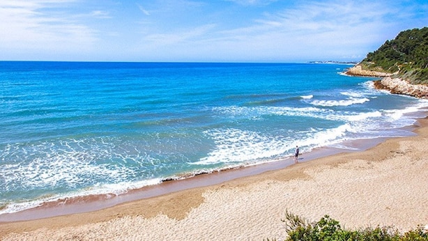 Ein Strand mit klarem, blauem Wasser und einem Sandufer.