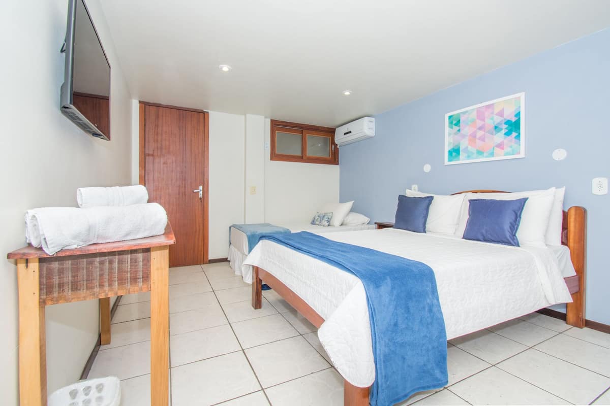 Ein Schlafzimmer mit Bett, Schreibtisch mit Stuhl, Fernseher und einer Tür.