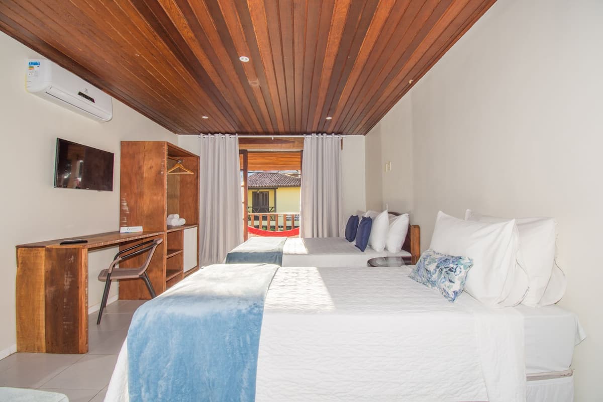 Ein Schlafzimmer mit Holzboden, einem Bett mit weißer und blauer Bettwäsche, einem Schreibtisch mit Stuhl und einem Fernseher an der Wand.