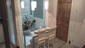 A dining area with a glass table, white chairs, and a wooden door. - Interior design and exclusive design (Sevilla)