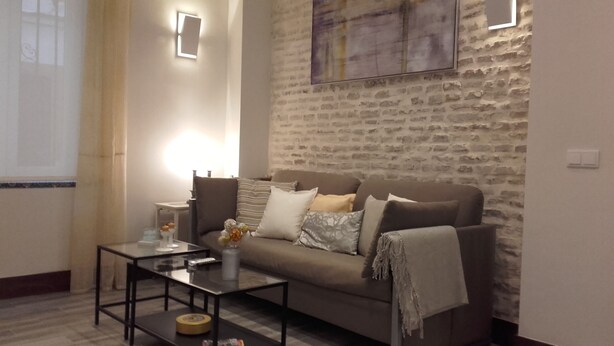 A living room with a sofa, a coffee table, and a wall-mounted light fixture. - Interior design and exclusive design (Sevilla)