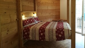 Ett rum inrett som en stuga, med träpanel, en säng, två sänglampor och ett fönster med utsikt.