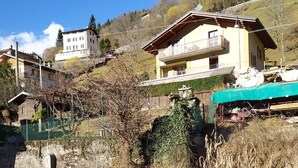 Ett bostadsområde med hus, ett grönt staket och en liten byggnad med en grund av betong.
