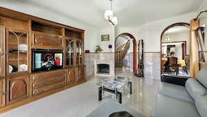 A spacious living room with a wooden entertainment unit, a glass coffee table, and a fireplace.