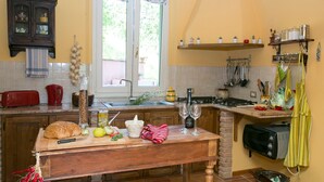 Eine Küche mit einem Holztisch, einem roten Toaster, einem Glasbehälter und einer Weinflasche.