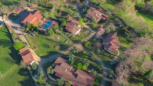 Vista aérea de una zona residencial con varias casas, céspedes verdes y una pequeña masa de agua.