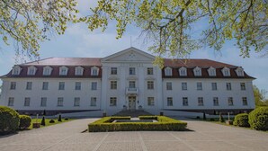 A large, symmetrical building with a central entrance, multiple windows, and a formal garden in front. - Seehotel Grossraeschen (Großräschen)