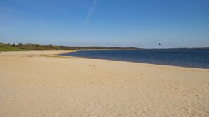A wide sandy beach with a calm body of water and a clear sky. - Seehotel Grossraeschen (Großräschen)