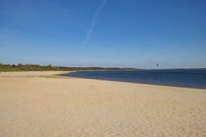 Une vaste plage de sable fin, avec une étendue d’eau calme et un ciel dégagé.