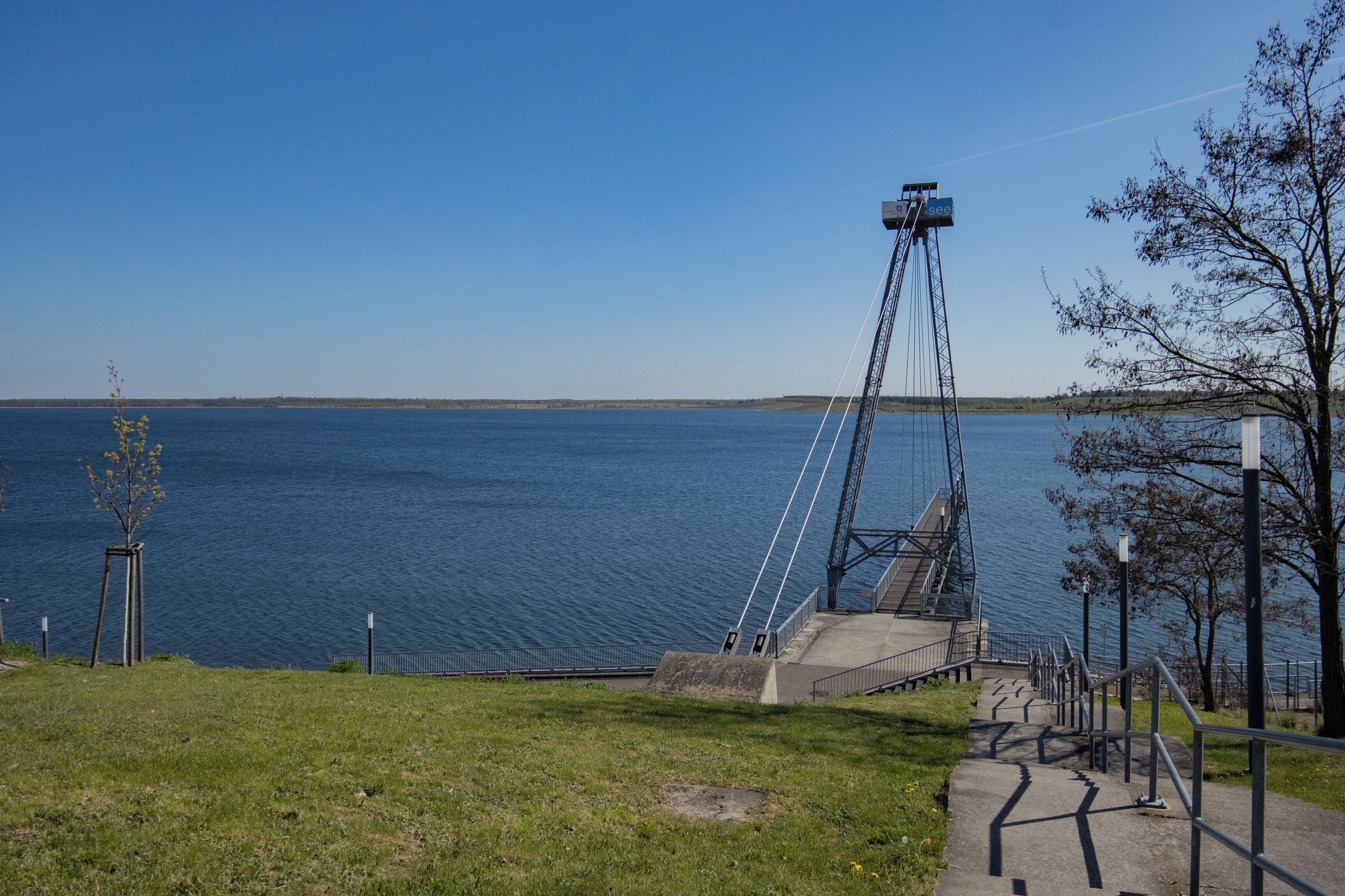 A coastal area with a bridge, a grassy path, and a body of water.