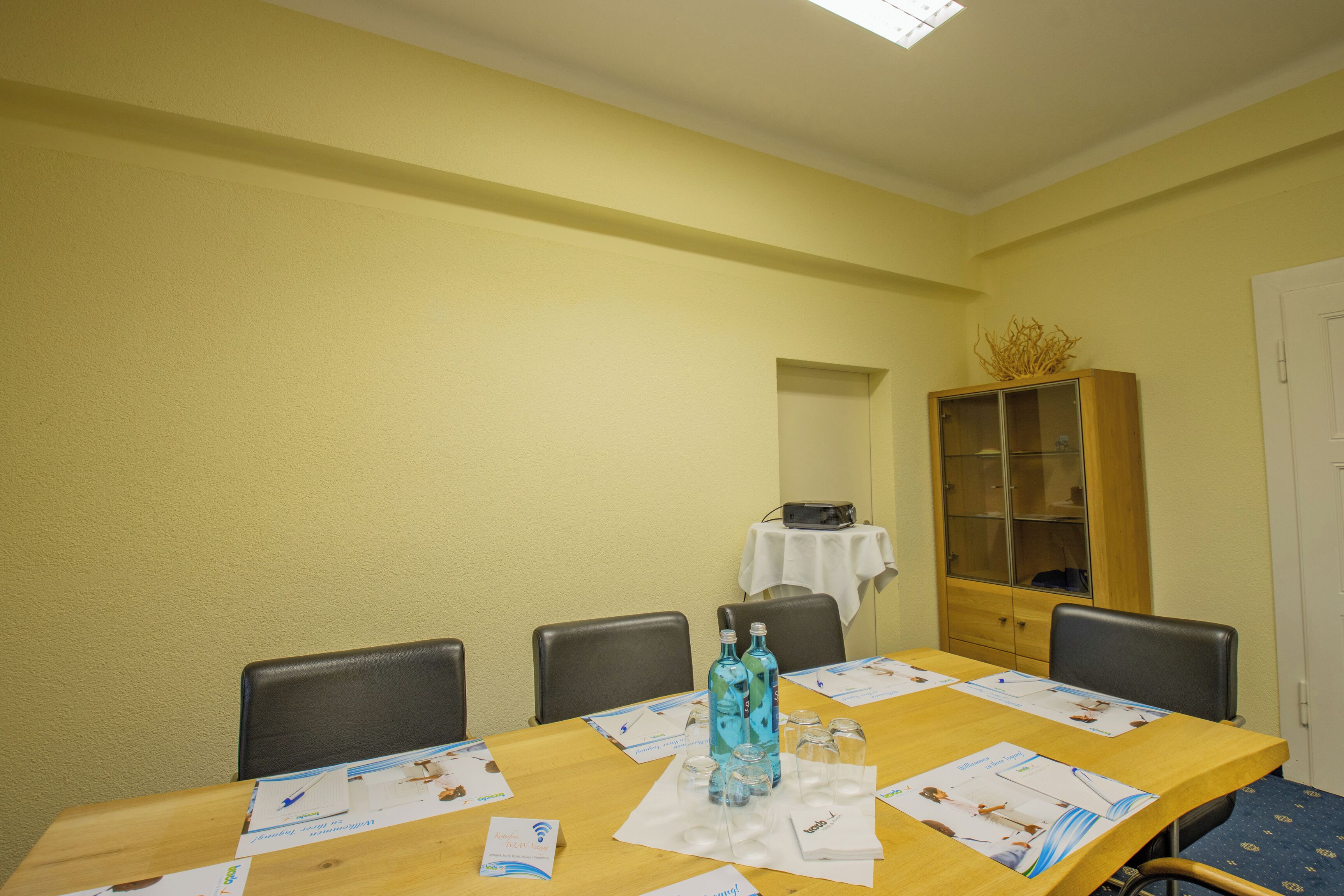 A conference room with a long table, chairs, a cabinet, and a white door.