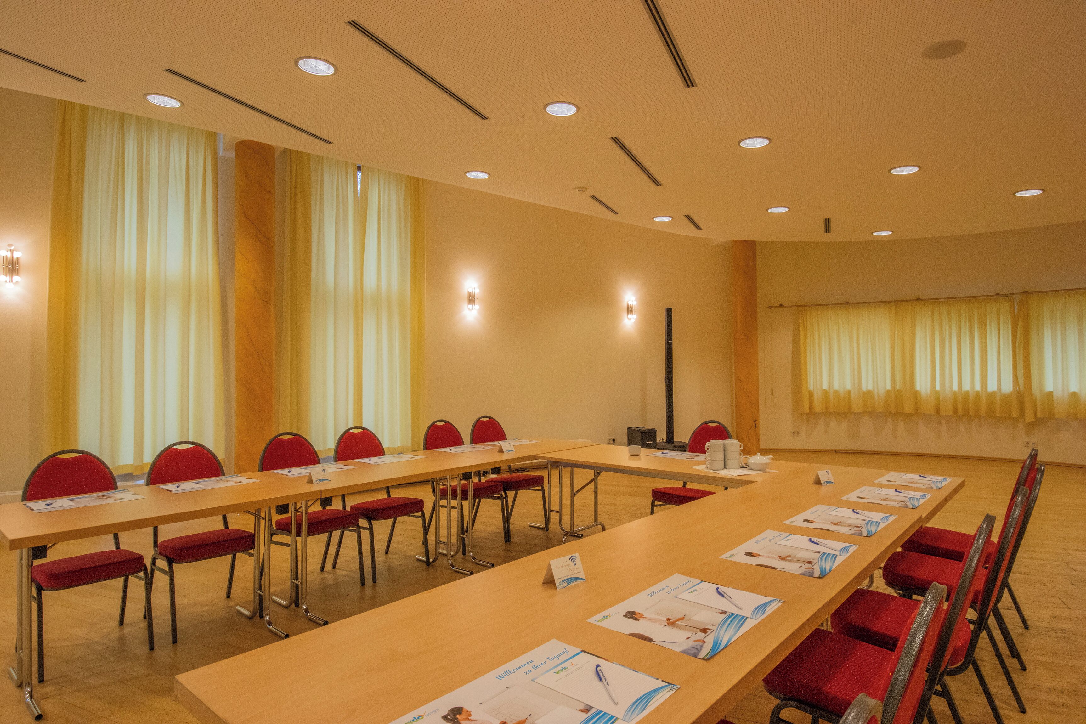 Une salle de conférence avec une longue table, des chaises rouges et des cartes nominatives.