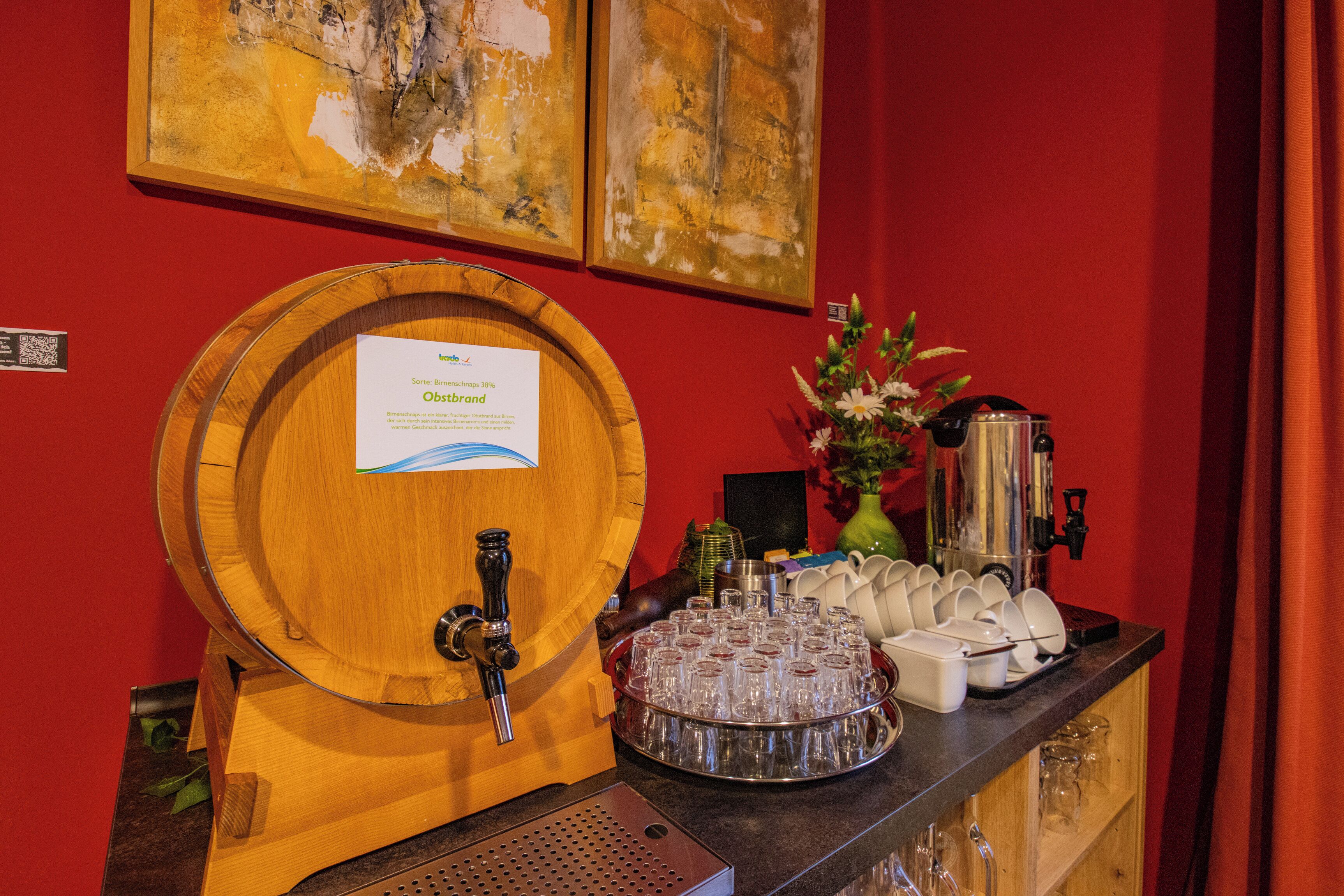 A bar area with a wooden barrel tap, a tray of glasses, and a coffee machine.