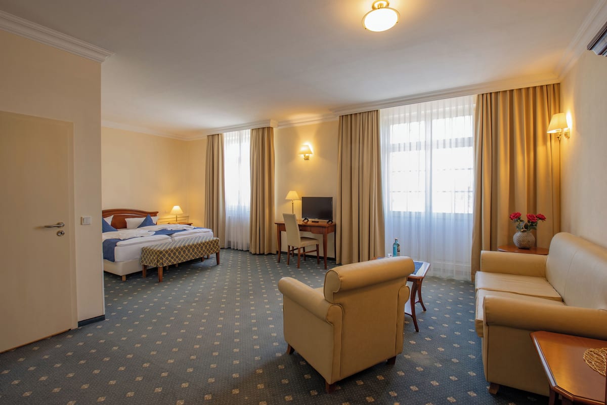 A hotel room with a bed, a desk, a TV, a sofa, and a small table.