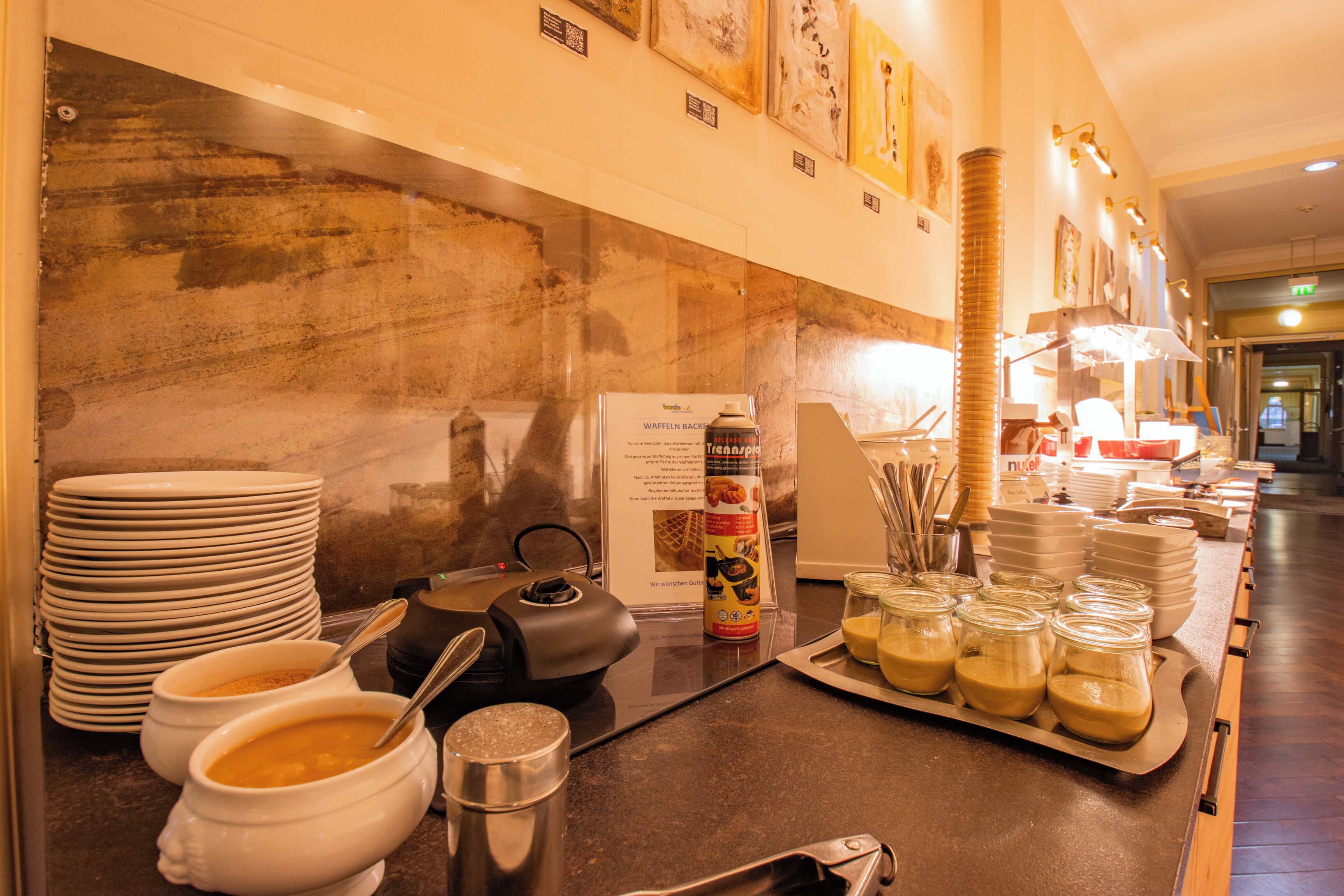 A buffet setup with bowls of soup, a waffle iron, and various condiments.