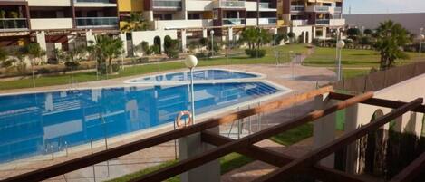 Un complex d'apartaments modern amb piscina, balcons i un jardí paisatjistic.