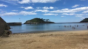 A beach with a rocky shoreline, a pier, and a small island with trees. - Mountain and Sea, The Basque Country (Gardata Artika (Bizkaia))