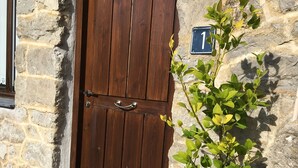 A wooden double door with a metal handle, a stone wall, and a number plaque. - Mountain and Sea, The Basque Country (Gardata Artika (Bizkaia))