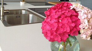 A kitchen with a stone wall, stainless steel sink, and a vase with pink and white flowers. - Mountain and Sea, The Basque Country (Gardata Artika (Bizkaia))