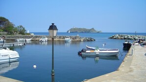 Un port tranquille, avec des bateaux amarrés, un mur de pierre et une vue dégagée sur la mer.