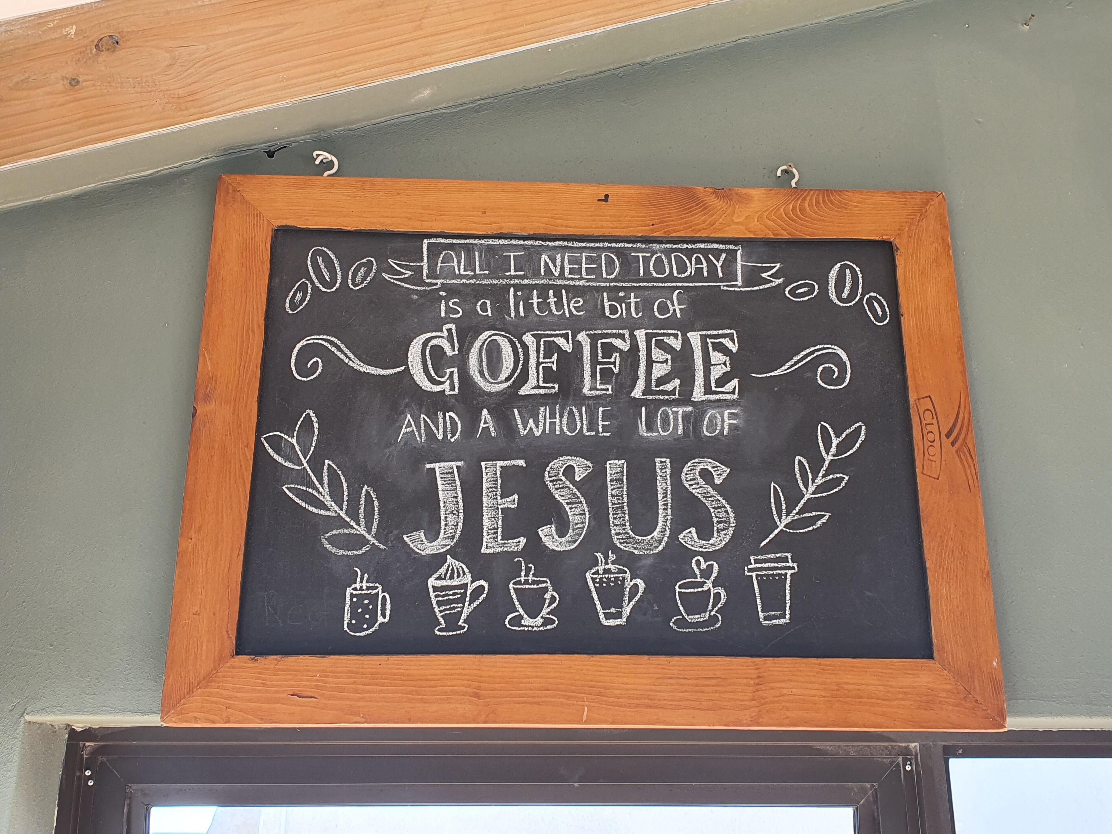 A chalkboard sign with a humorous message about needing coffee and Jesus.