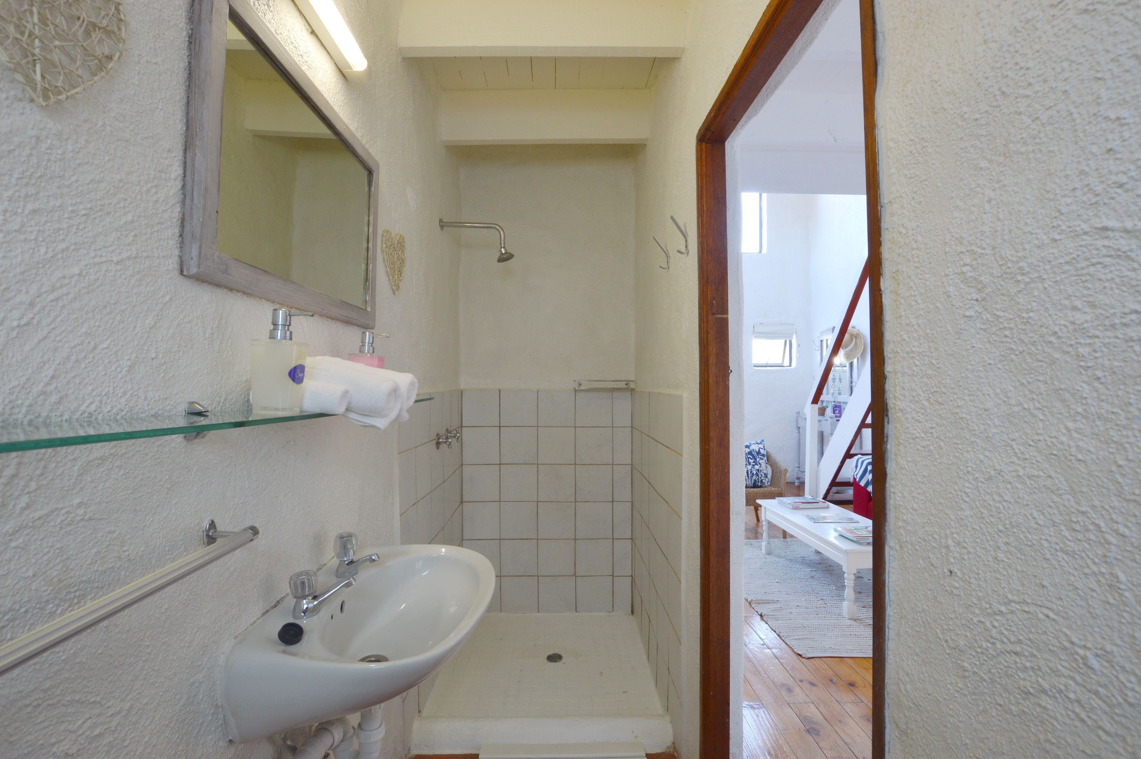 A bathroom with a sink, mirror, and shower.