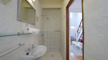 A bathroom with a sink, mirror, and shower.