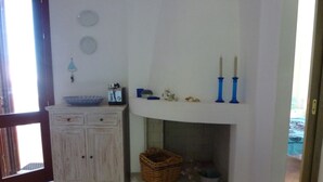 A room with a white cabinet, a fireplace, a basket, and a window.