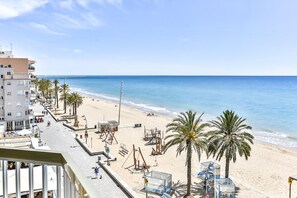 A beachside hotel with a long promenade, palm trees, and a view of the sea.