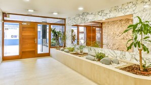 Eine moderne Lobby mit Marmorwänden, einer Rezeption und einer Pflanzengestaltung.