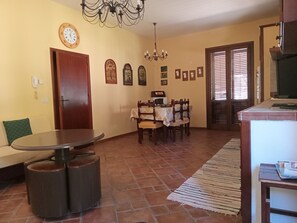 A dining area with a round table and chairs, a chandelier, and a clock on the wall.