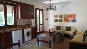 A kitchen with wooden cabinets, a washing machine, and a dining area with a sofa and table. - ✭Autonomous villa of recent construction in the island of Favignana (EGADI) (Favignana)