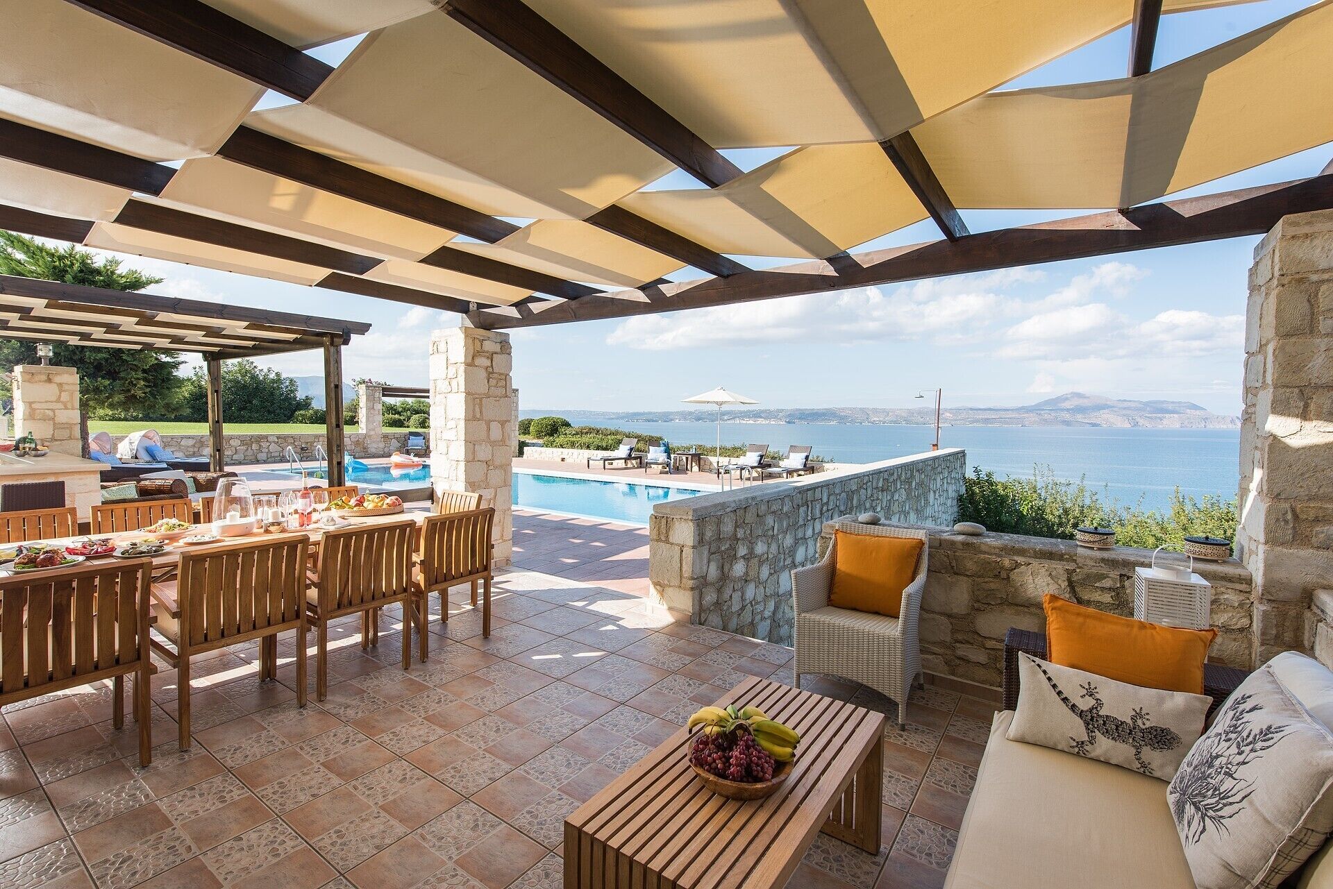 Un patio exterior con piscina, zona de comedor y asientos con vistas al agua.