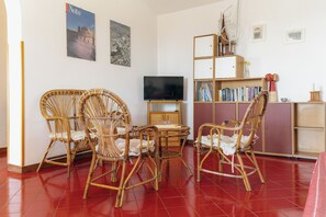 Cozy living space with a flat-screen TV, wicker chairs, and a bookshelf.