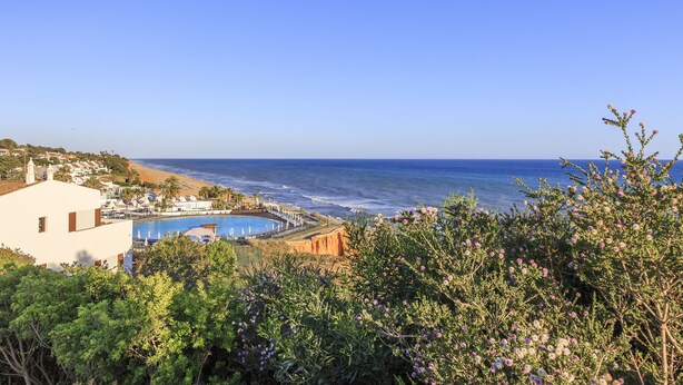 Ein Küstenhotel mit Pool, Zugang zum Strand und üppiger Bepflanzung.