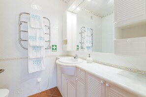 A bathroom with a white sink, a mirror, and two towel racks with towels hanging. - CASAS DA PRAIA, 56 (Almancil)