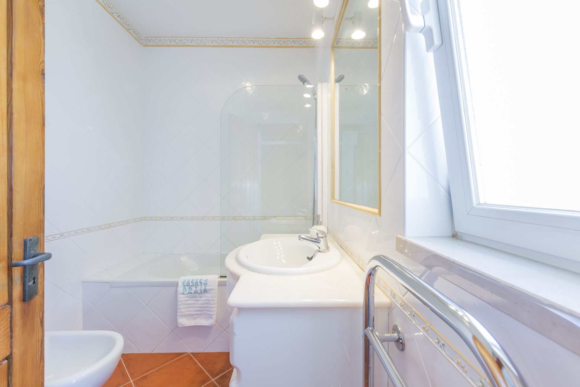 Een badkamer met een wit wastafel, bad en douche.