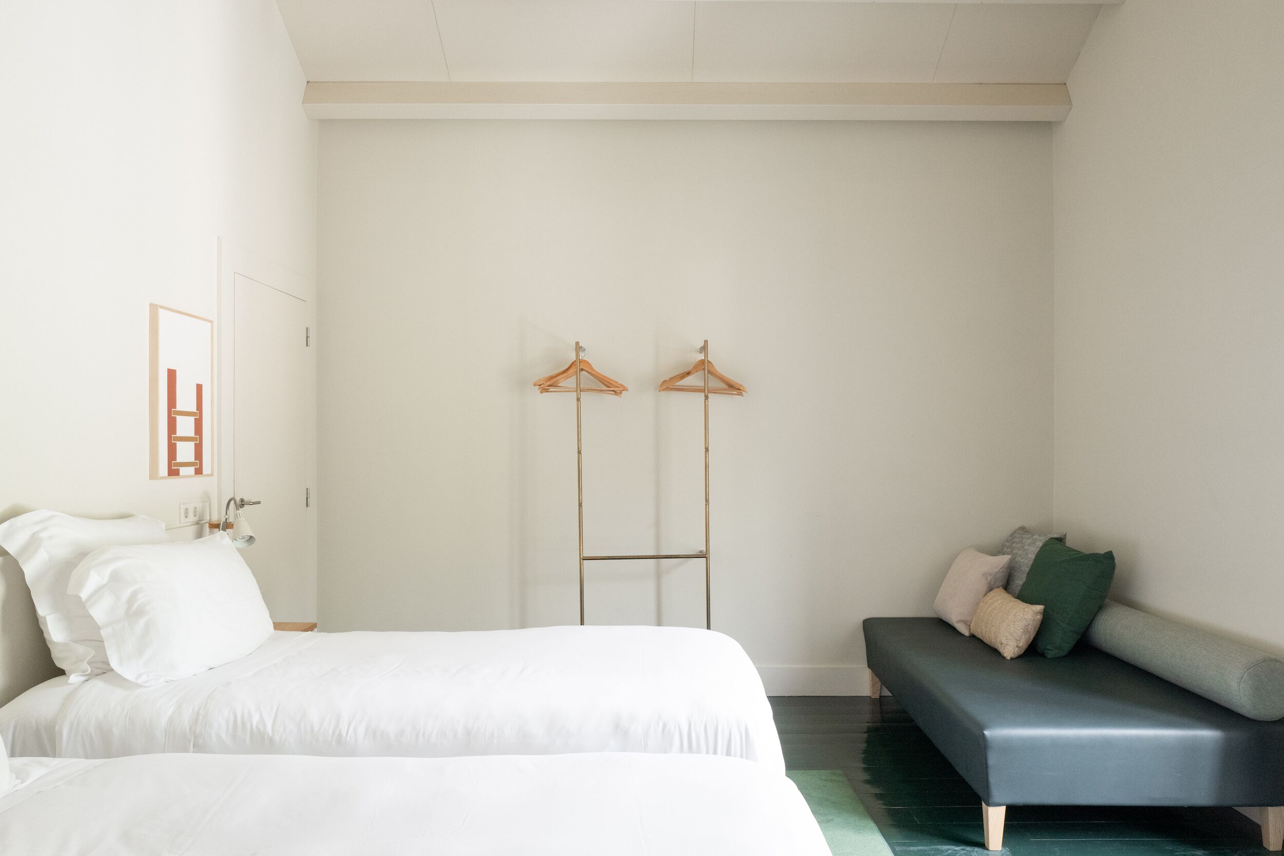 A bedroom with a bed, a sofa, and two wooden hangers on the wall.