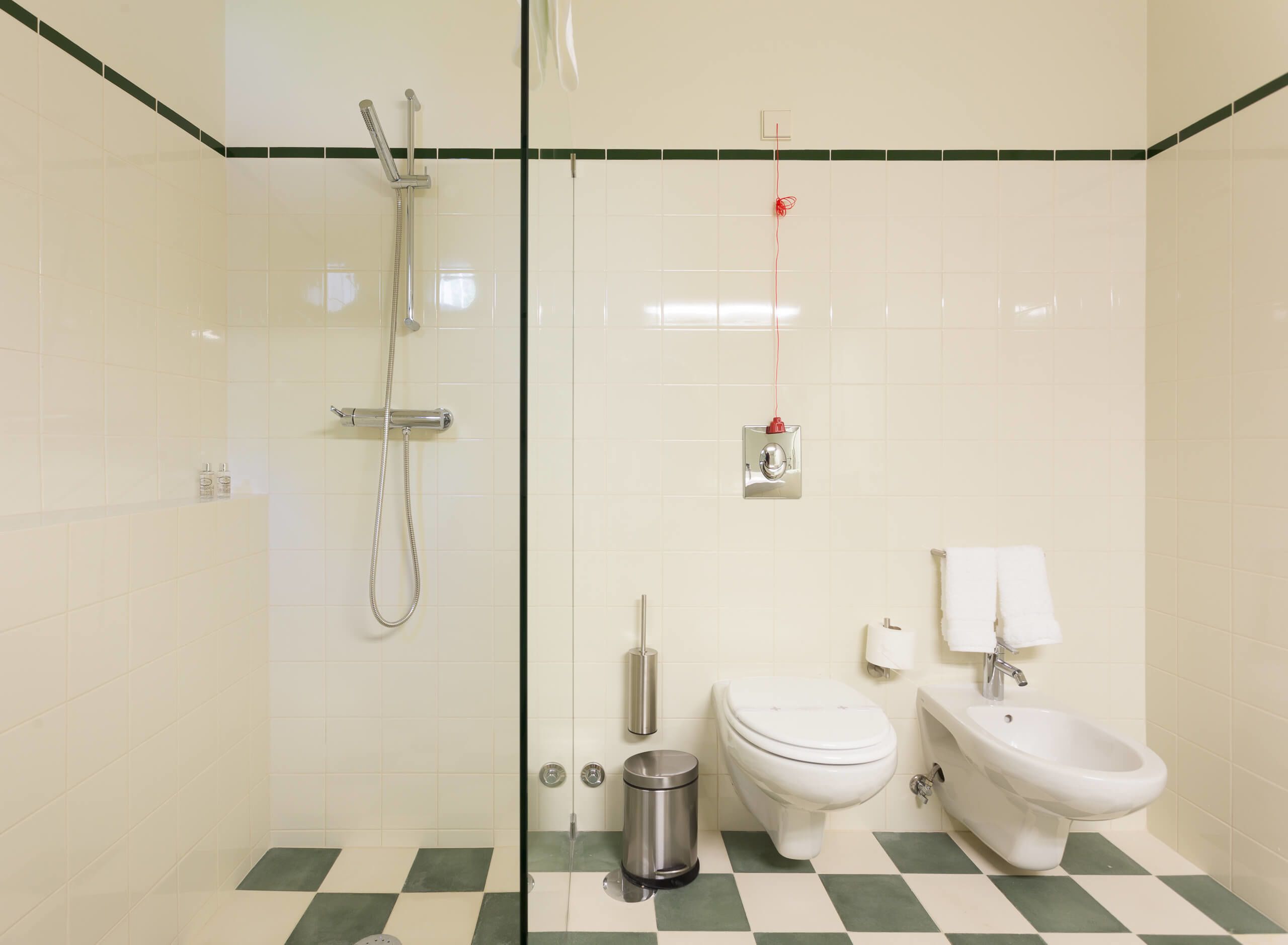 Une salle de bain équipée d’une douche, de toilettes, d’un bidet et d’une poubelle.