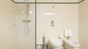 Une salle de bain équipée d’une douche, de toilettes, d’un bidet et d’une poubelle.