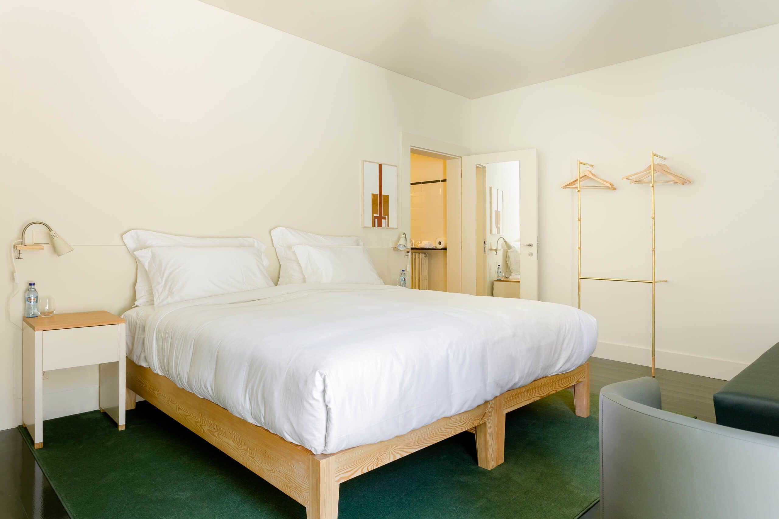 Una camera da letto ordinata con un letto di legno, un comodino con una lampada e uno specchio.