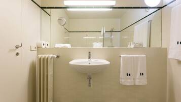 Une salle de bain avec un lavabo blanc, un miroir, un porte-serviettes avec des serviettes et un radiateur.