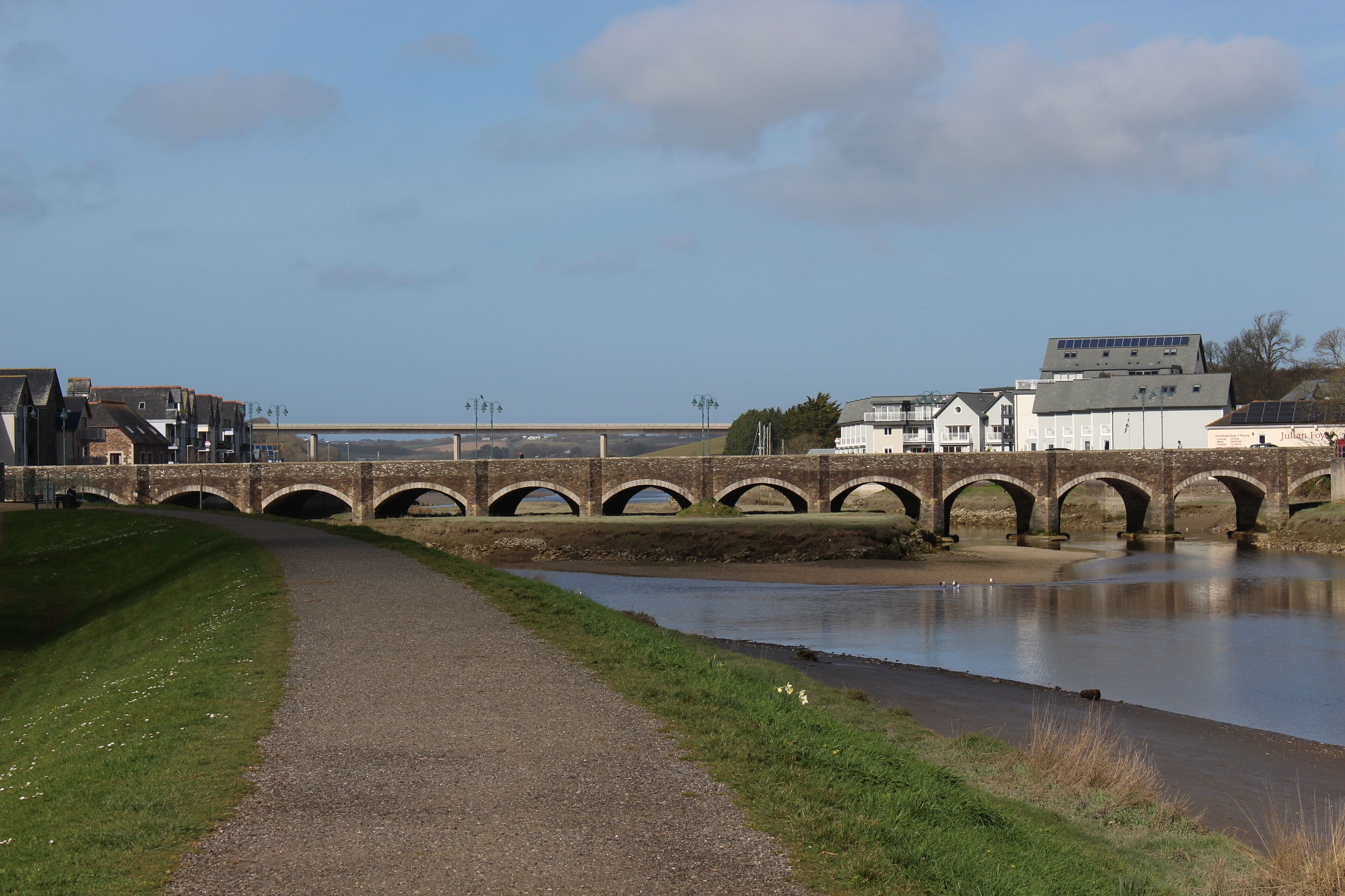 A stone bridge over a river with a path beside it.