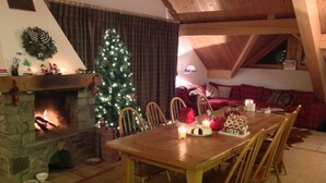 Ein gemütliches Wohnzimmer mit Kamin, Esstisch und Weihnachtstannenbaum.