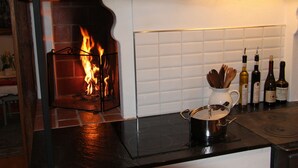 A kitchen with a fireplace, a pot on the stove, and several bottles of wine on the counter. - Nice old style cottage close to the Baltic Sea (Gryt, Valdemarsvik)