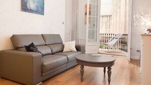 Un salon moderne avec un canapé gris, une table basse ronde et un tableau accroché au mur.
