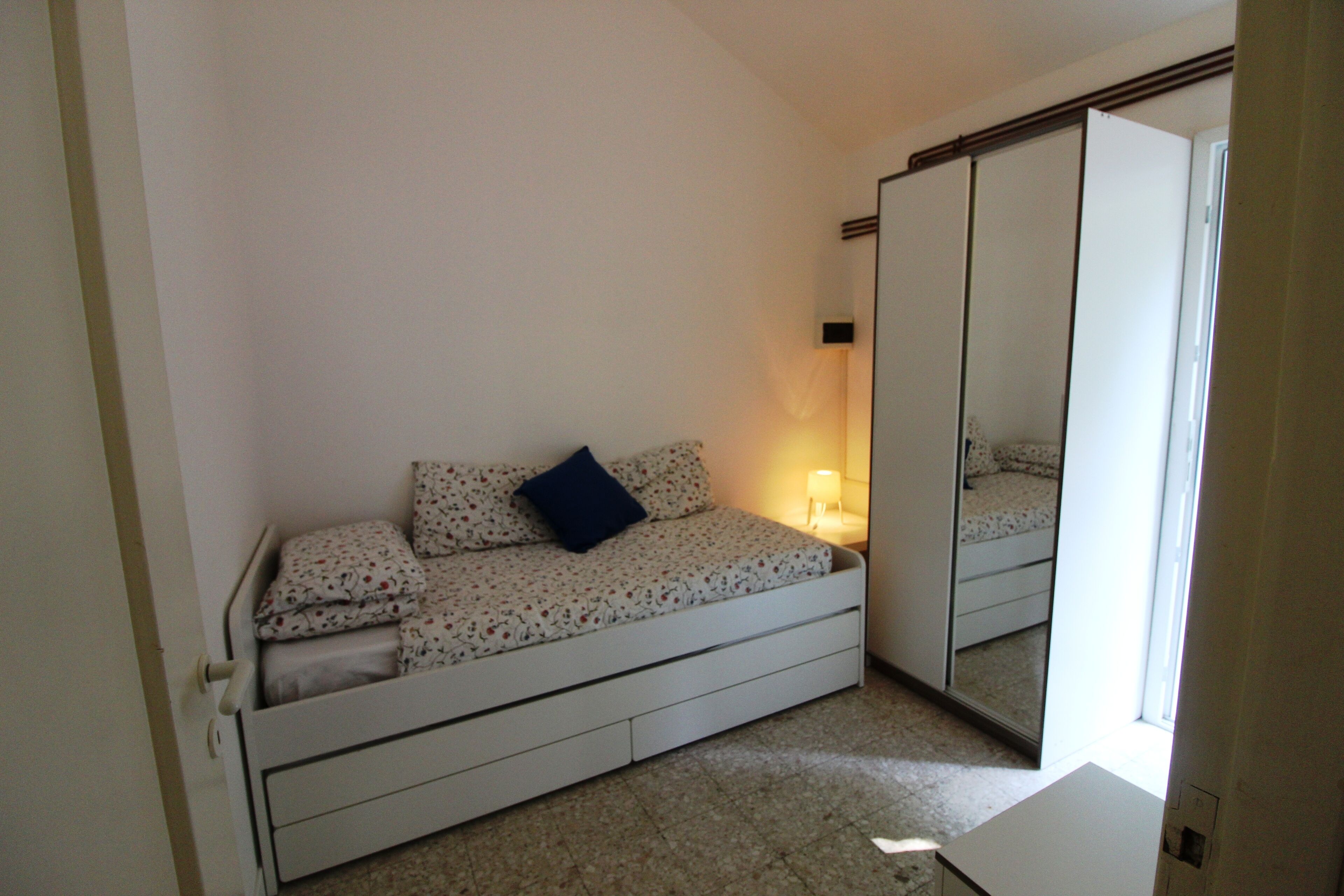 Une chambre à coucher avec un lit, une table de chevet, un miroir et une armoire.